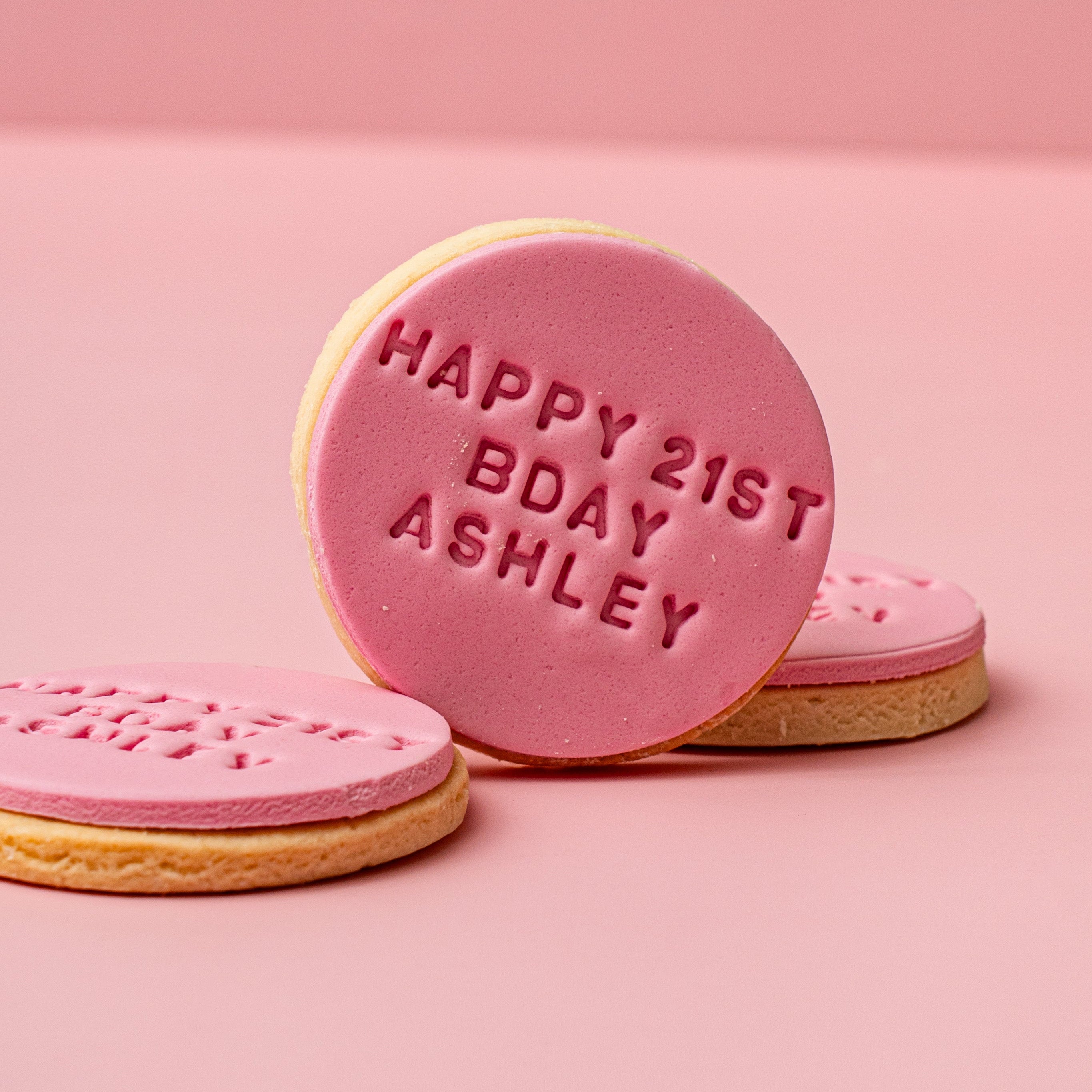 Pink cookies with 'Happy 21st Birthday Ashley' text on a pink background