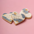Heart-shaped cookies with personalized inscriptions on a pink background