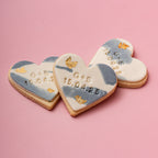 Heart-shaped cookies with personalized inscriptions on a pink background