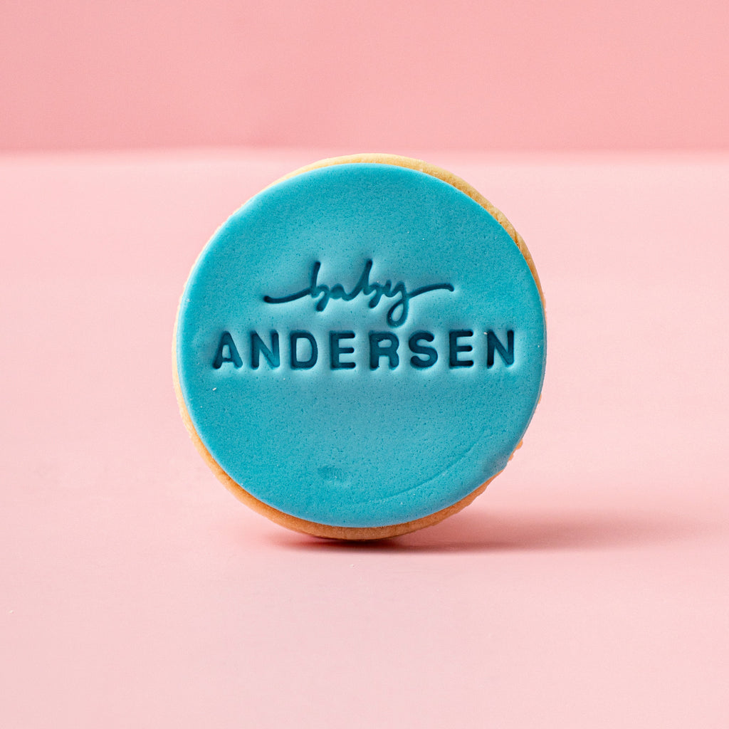 Round blue cookie with 'baby Andersen' text on a pink background