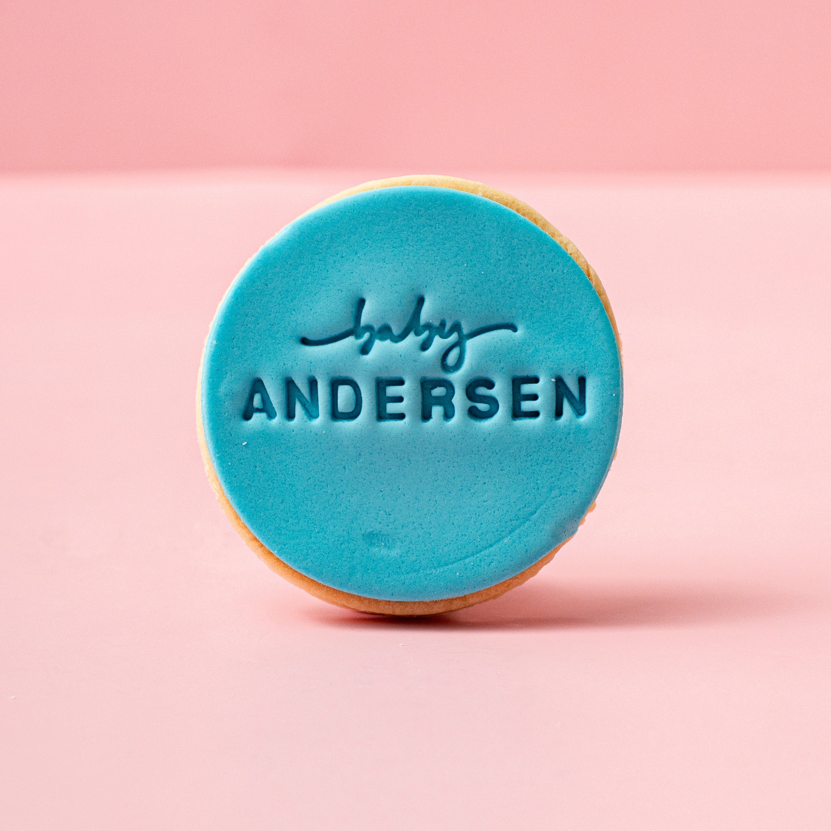 Round blue cookie with 'baby Andersen' text on a pink background