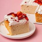 Slice of cake with whipped cream and strawberries on a pink background