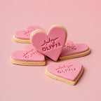 Heart-shaped cookies with 'Julia Olivia' branding on a pink background