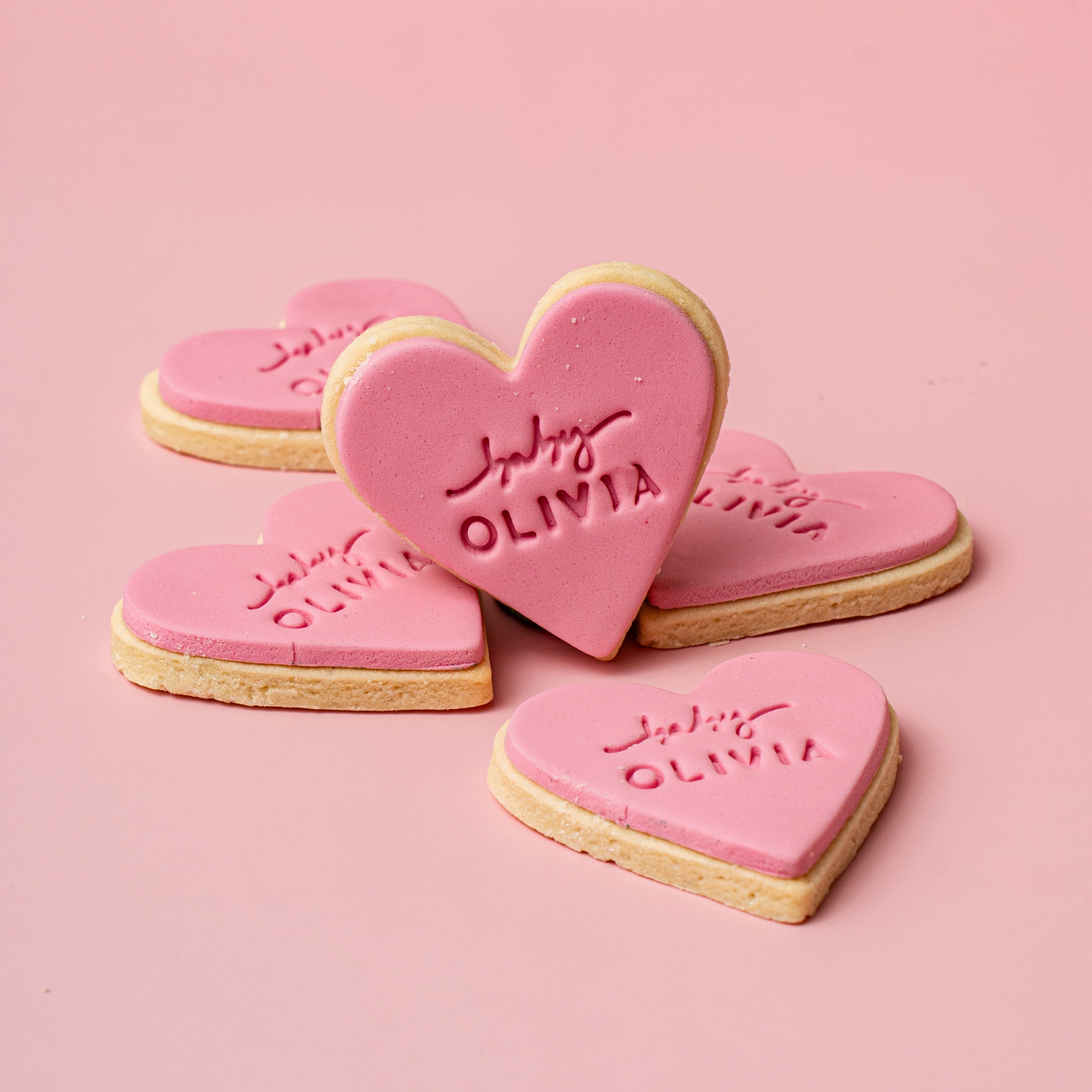 Heart-shaped cookies with 'Julia Olivia' branding on a pink background