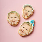 Three cookies with faces of a baby on a pink background
