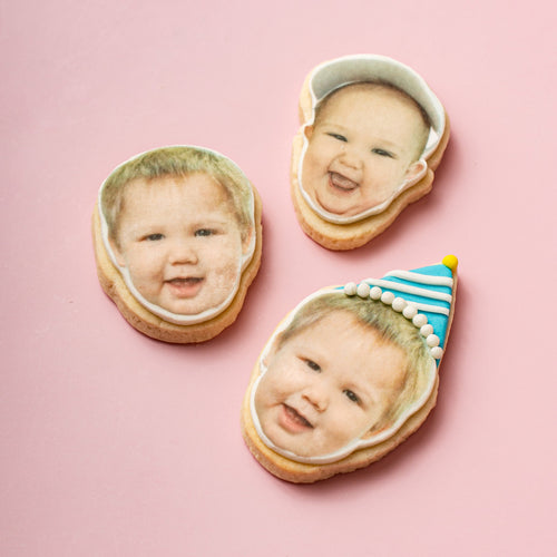 Three cookies with faces of a baby on a pink background