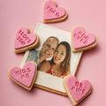 Heart-shaped cookies with Valentine's Day messages around a photo of a couple on a pink background